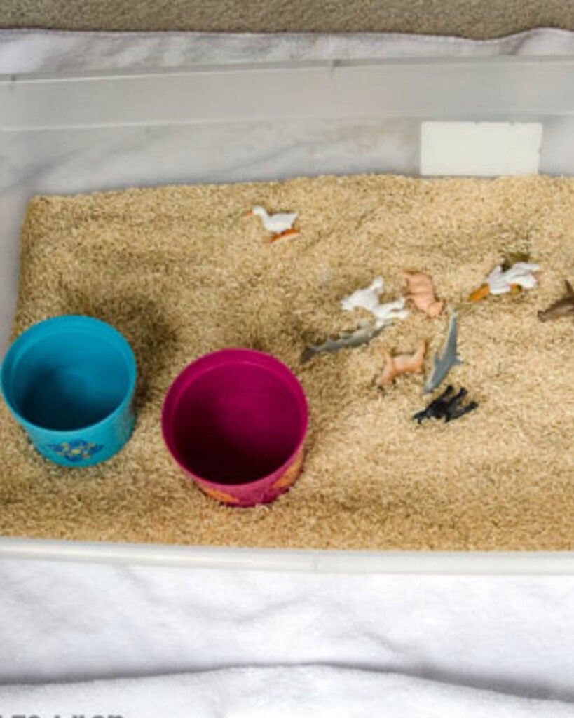 A rice sensory bin made with buckets and animals.