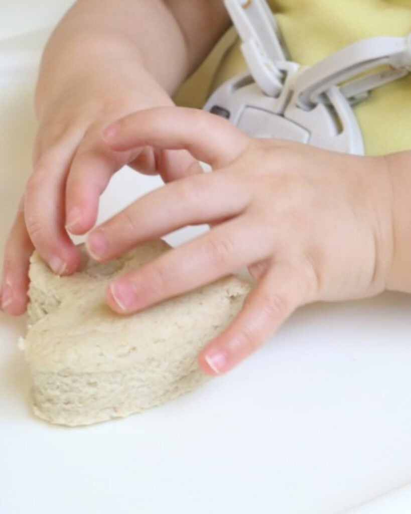 A child's hands play with baby-safe play dough