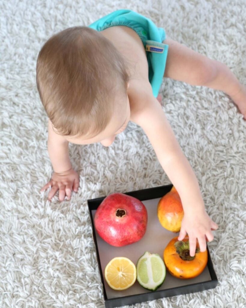 A child explores a sensory discovery basket of fruit.