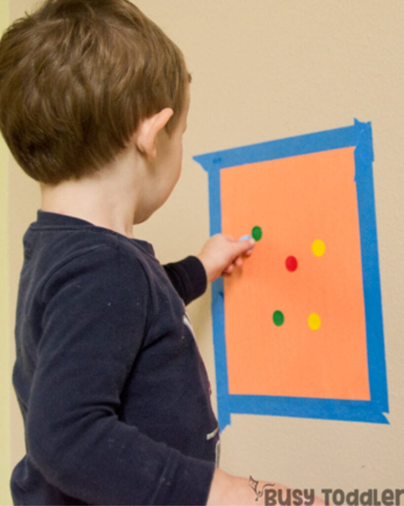 A child pushes a dot stickers onto construction paper.
