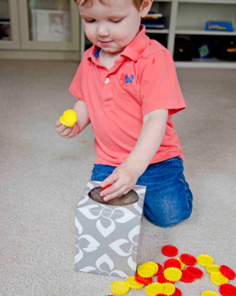 A child places poker chips into a box.
