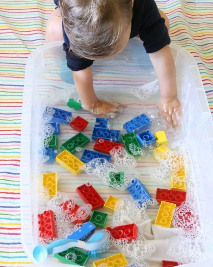 A child washes LEGO Duplo bricks in water.