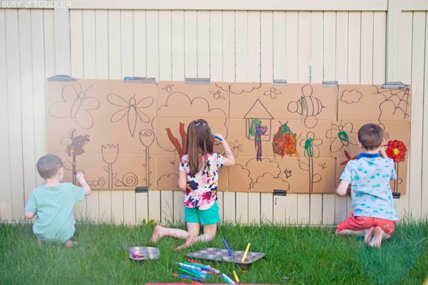 Kids painting on a cardboard box with a giant art project.