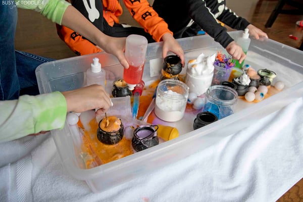 3 kids playing with a Halloween science bin creating different potions with different materials