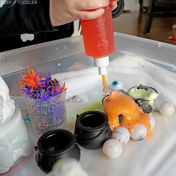 Orange vinegar squirts from a peri bottle into a mini cauldron full of baking soda.
