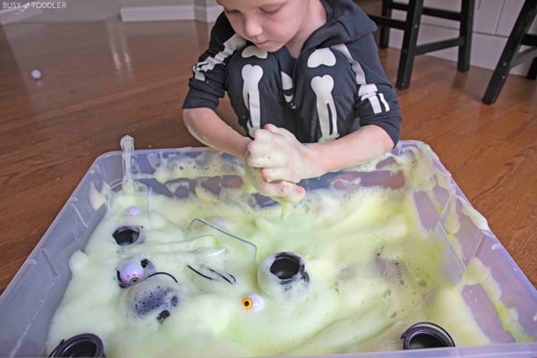 A child playing with a Halloween themed sensory bin made of bubble foam
