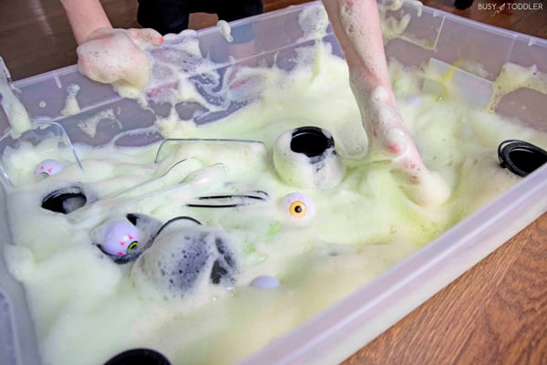 A child playing with a Halloween themed sensory bin made of bubble foam