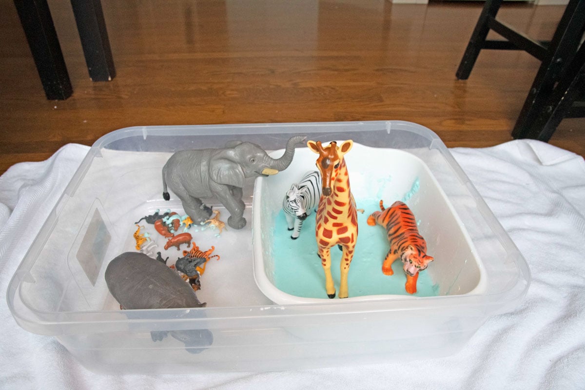 A sensory bin of oobleck waits for play. It is full of large and small toy animals.