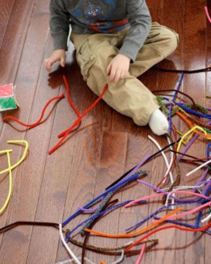 A child picks up pipe cleaners.