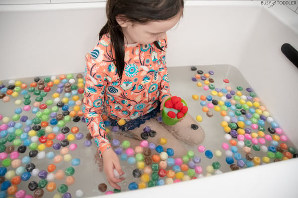 A child plays in a bath filled with pom pom balls