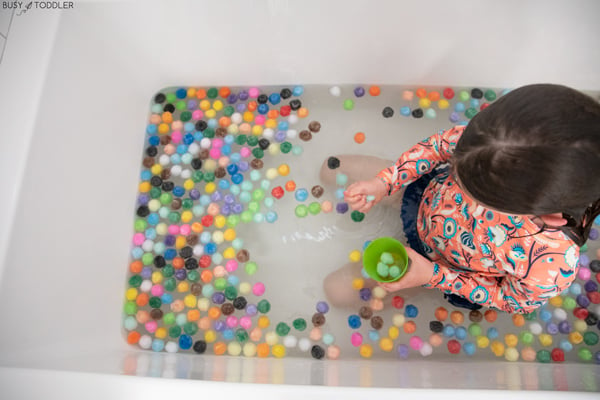 A child plays in a bath filled with pom pom balls