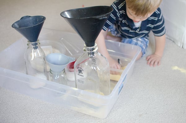 A toddler playing with a fun sensory scooping activity from Busy Toddler