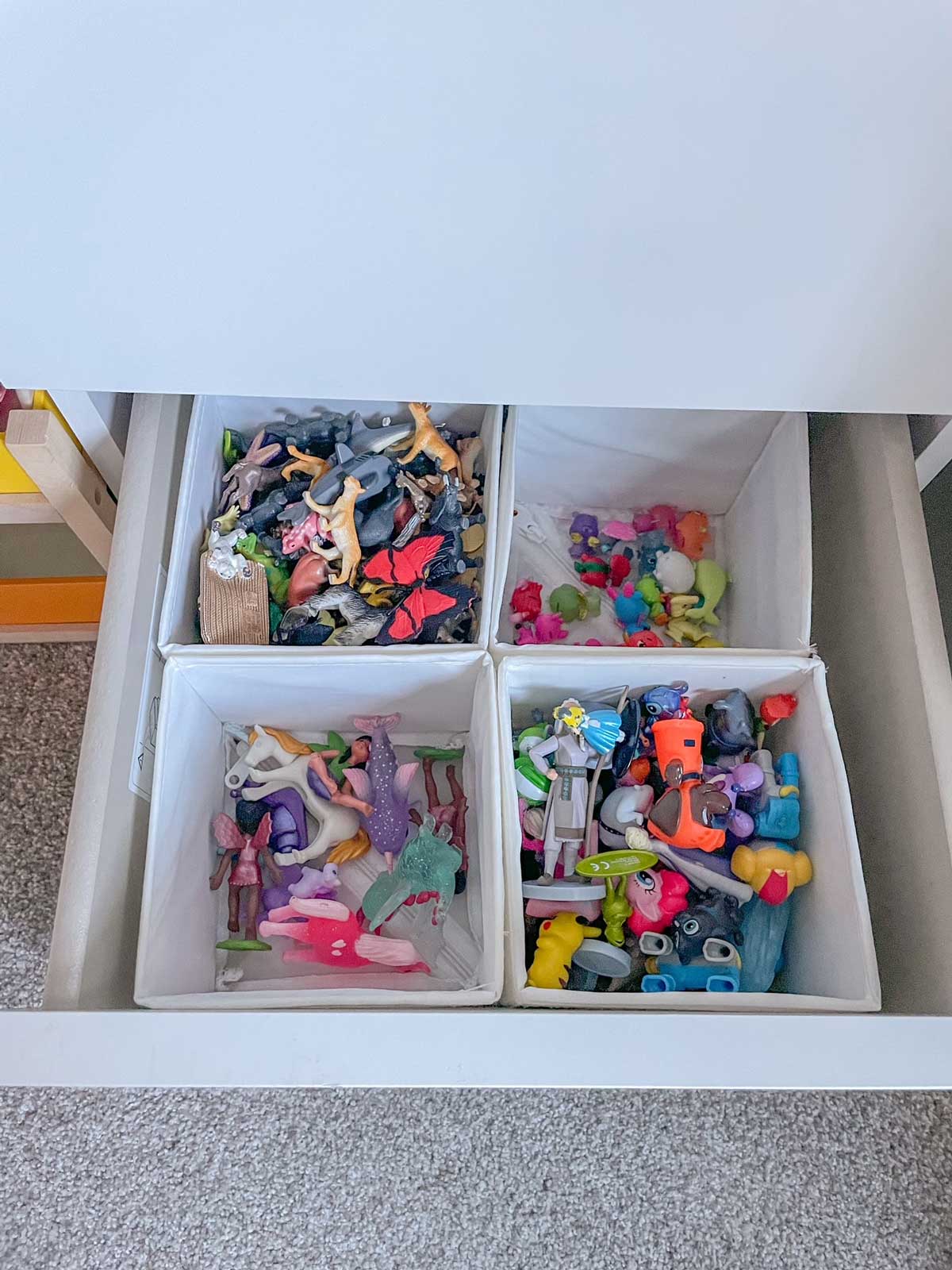 A drawer full of small animal toys separated into cubes