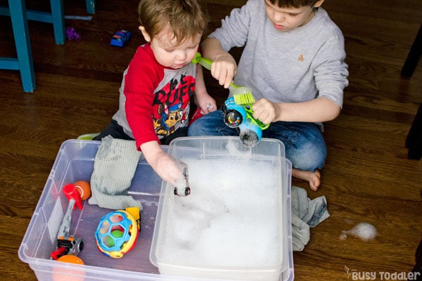 Two boys sit at a kids activity washing toys.