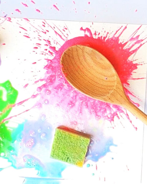 A wooden spoon splatters a paint soaked sponge