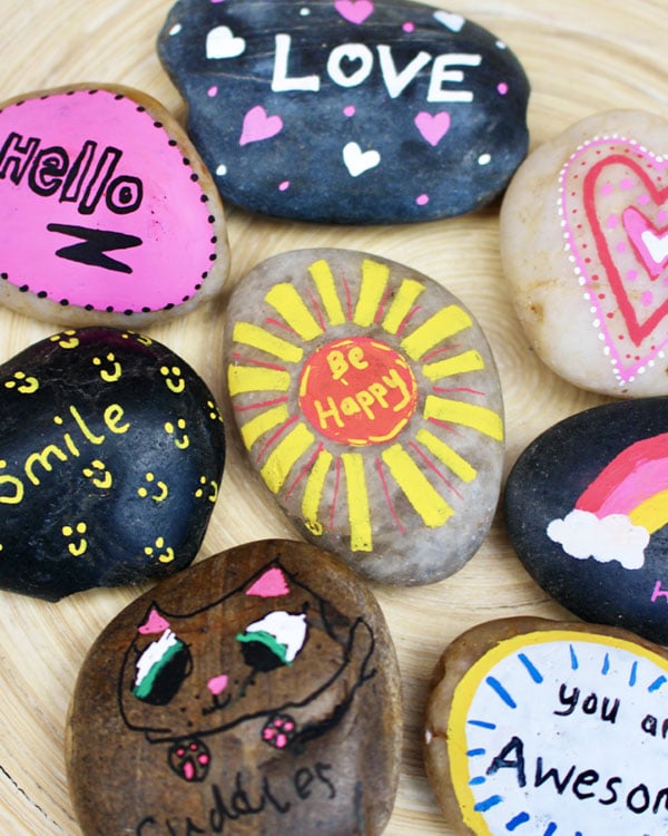 Rocks painted with decorates like hello, smiley faces, and love.