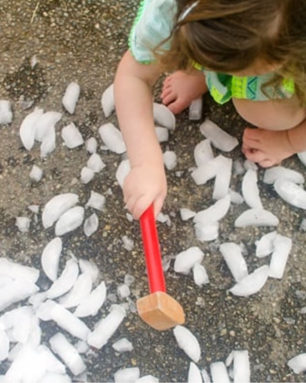 A child smashes ice with a toy hammer