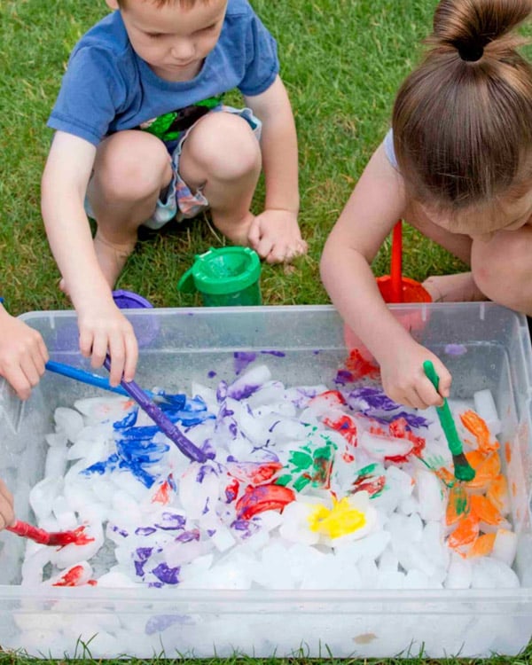 Two children paint ice cubes.