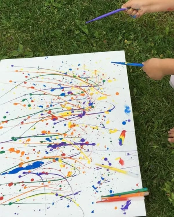 A child splatters paint with a pipette