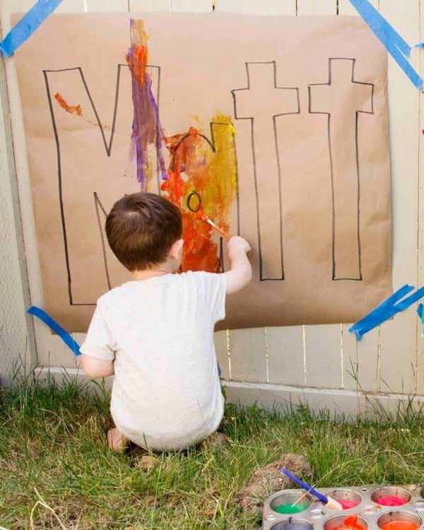 A child paint his name in large letters