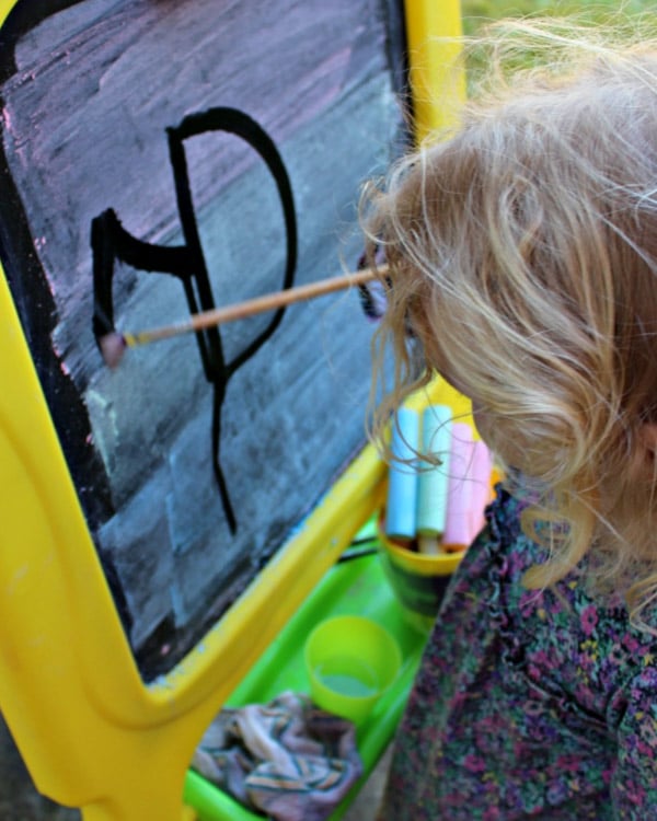 A child paints with water on a chalk board.
